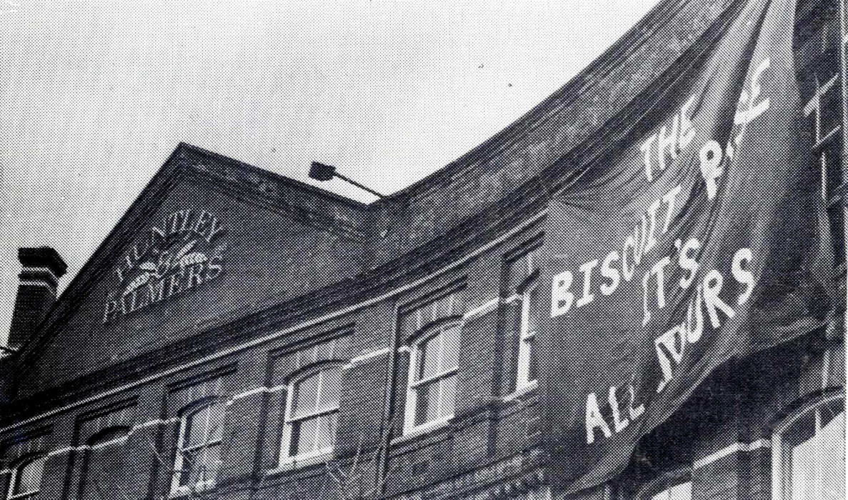 Part of Huntley and Palmers building with large banner with writing, 1990 ref. D/EX2800/3/6