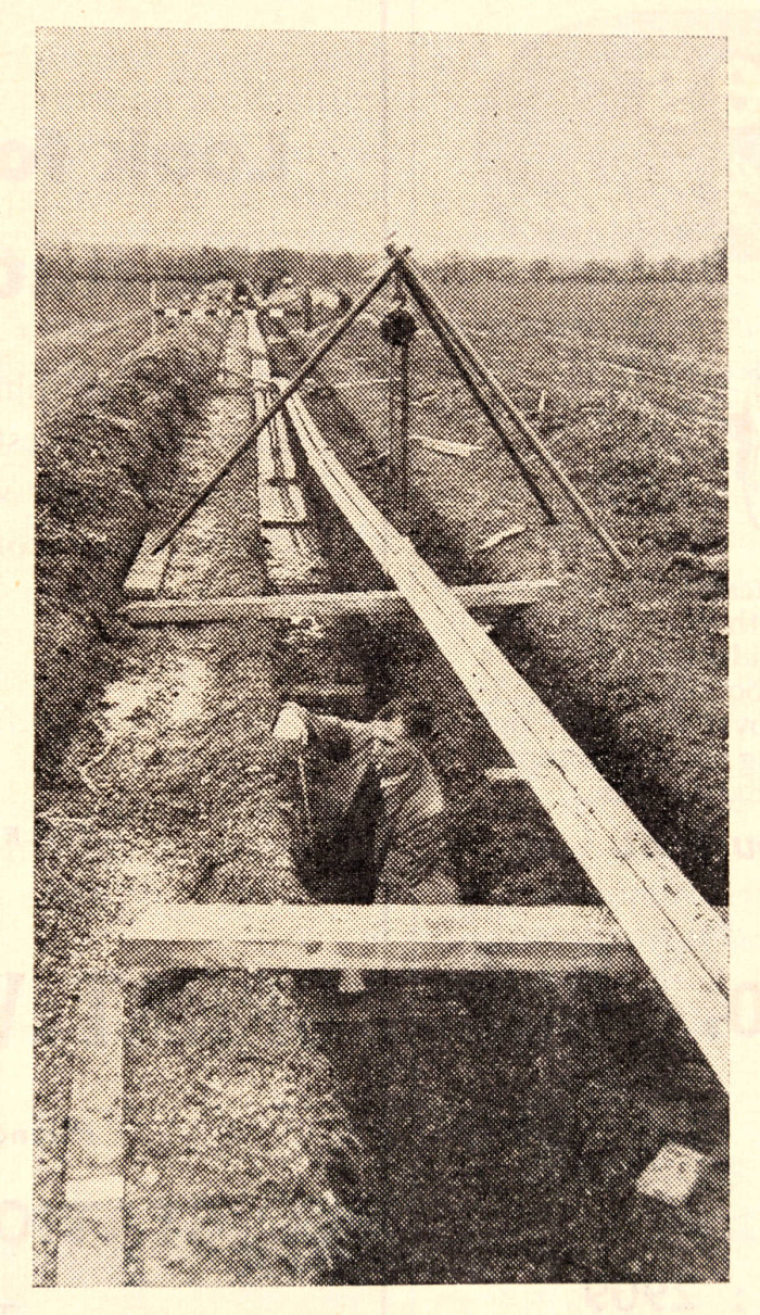 Man stands in a ditch trench for a pipeline ref. D/EX2686/5