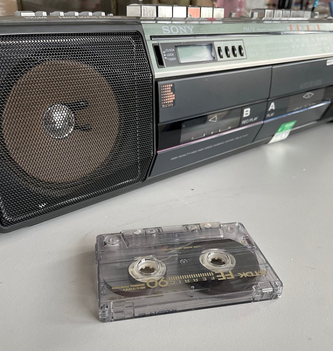 A cassette tape on a table with a cassette player behind it