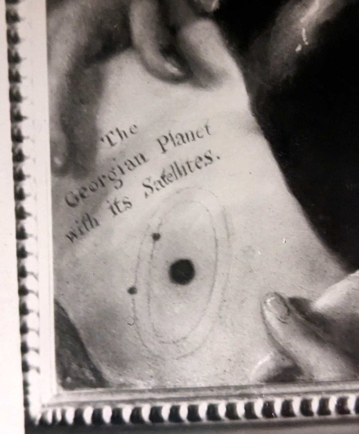 Close up from a black and white photograph of a portrait of Sir William Herschel showing the words 'The Georgian Planet with its satellites' ref. WI/151/1