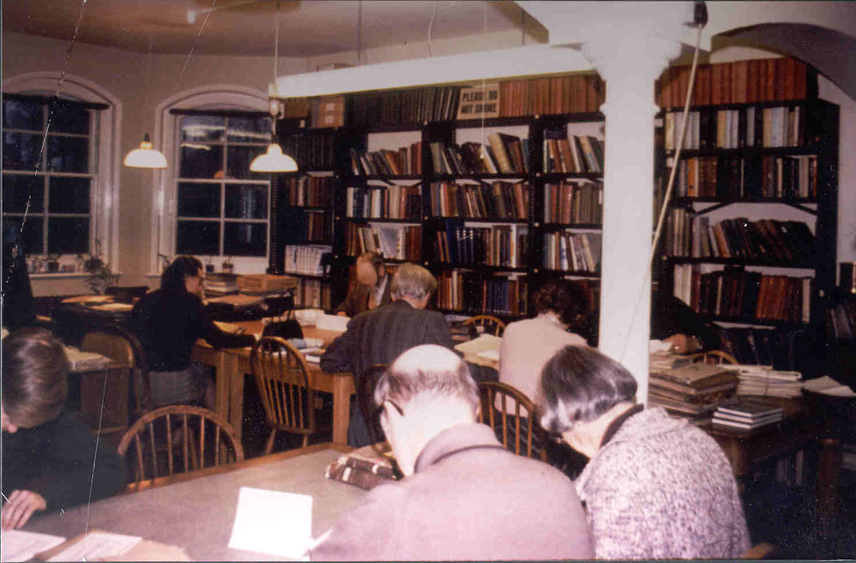 The searchroom of the Forbury, Reading 1979. Several people sit at desks looking at archives.